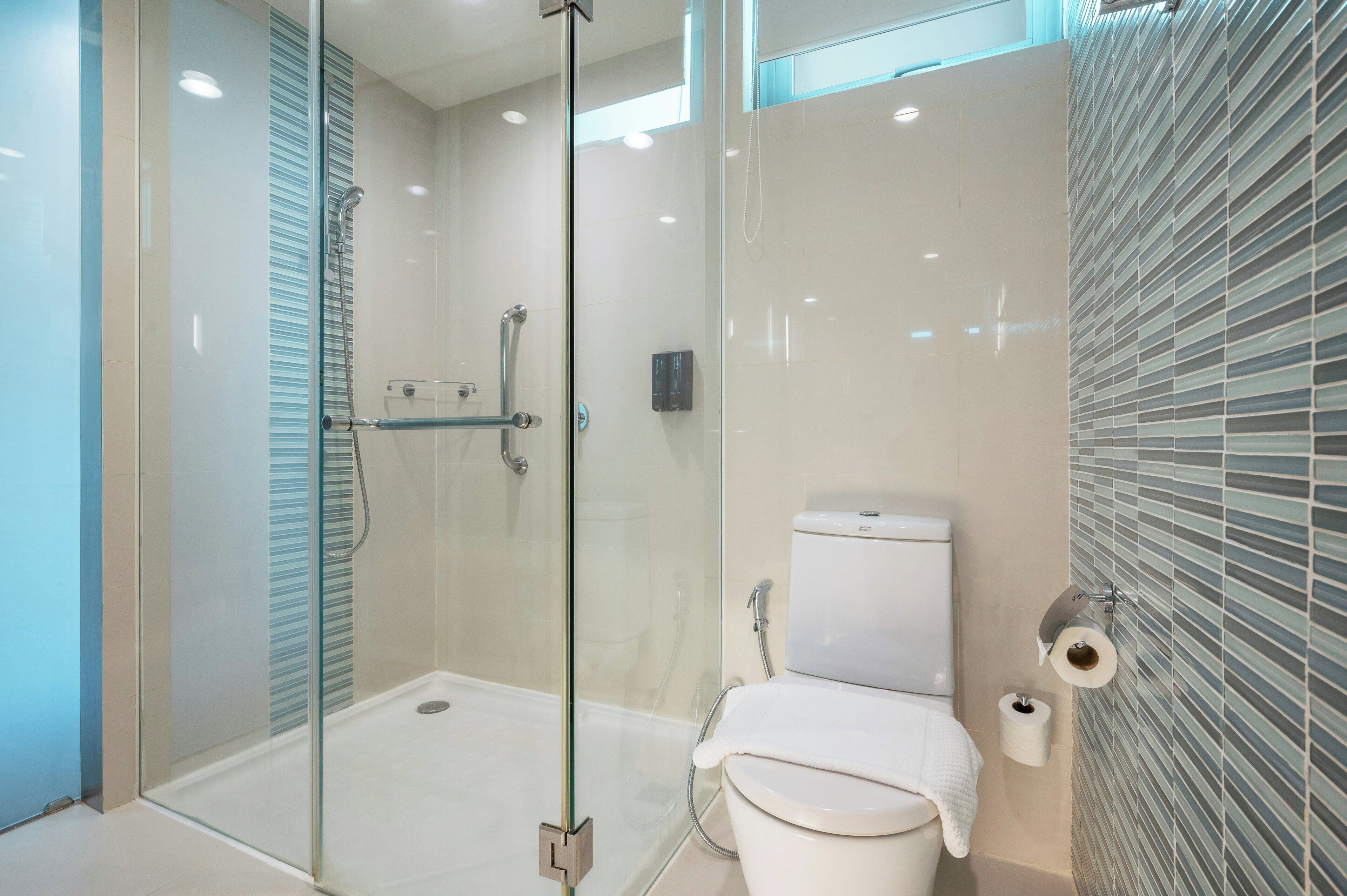 A modern bathroom with a glass-enclosed shower, a toilet, and a toilet paper holder.