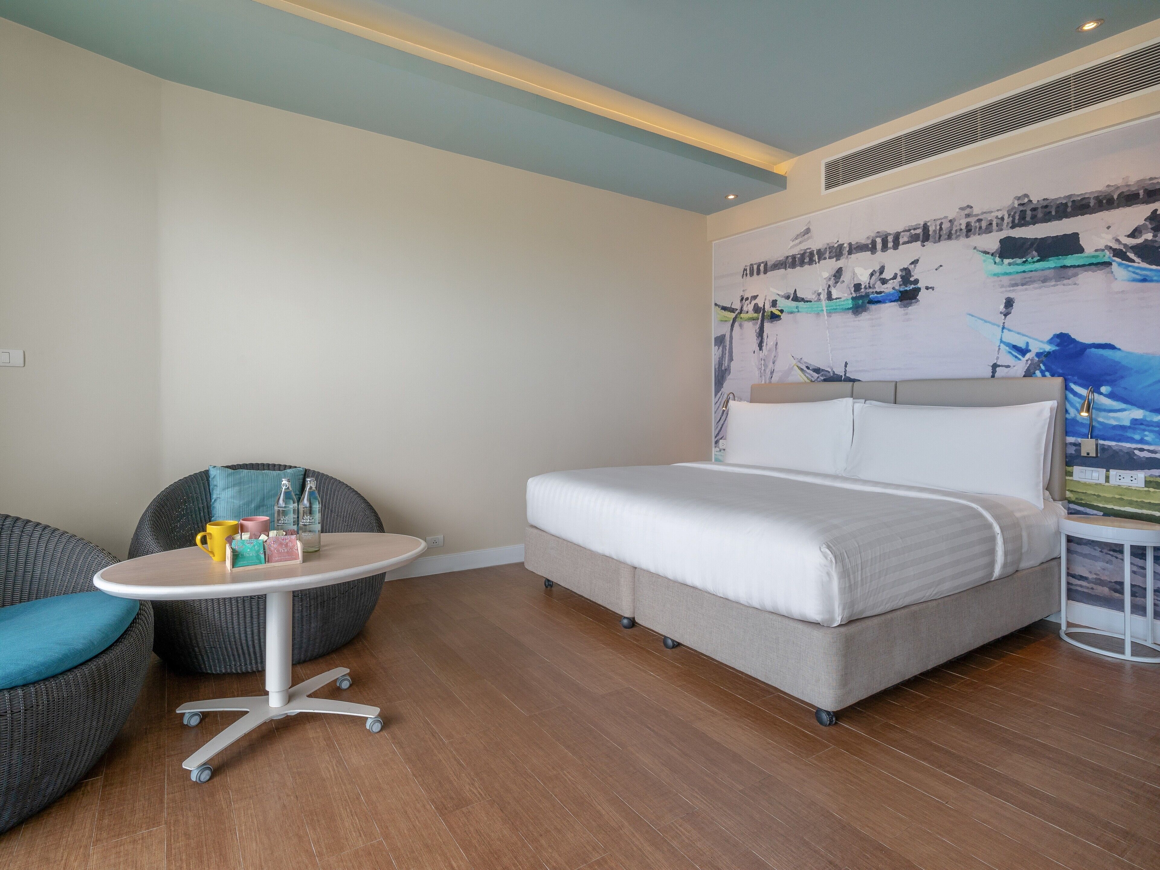 A hotel room with a bed, a round table with chairs, and a wall-mounted artwork.