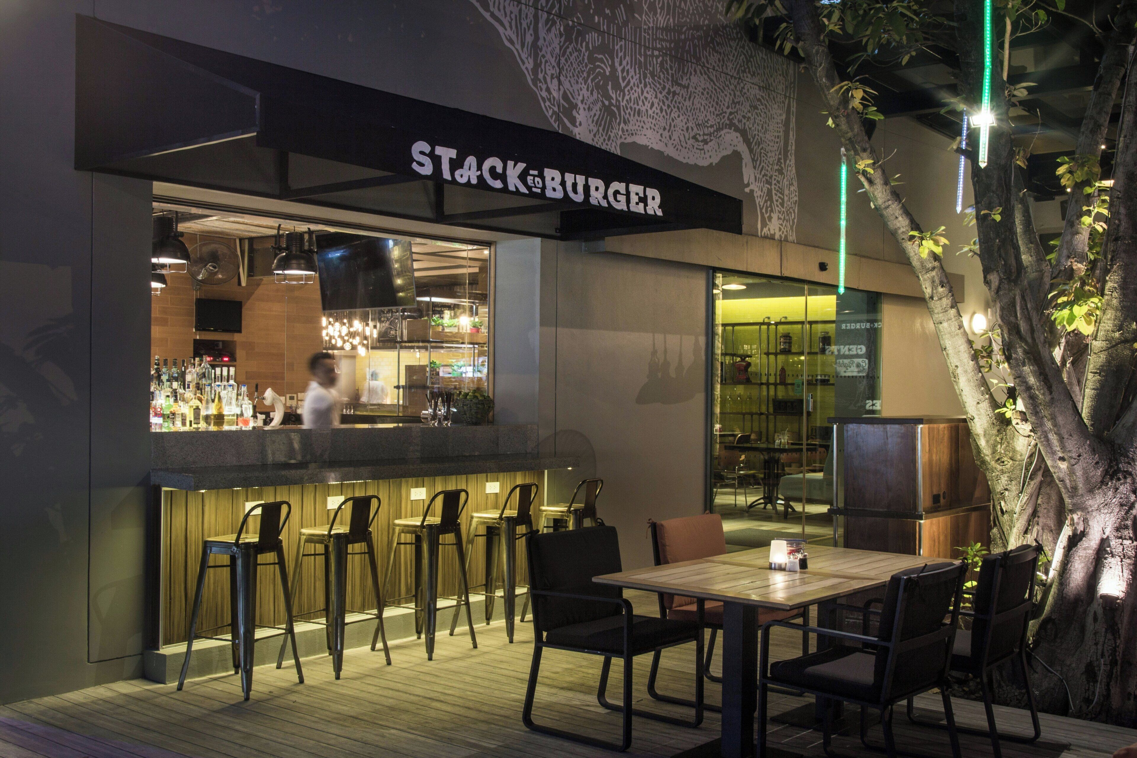 A restaurant with a bar area, outdoor seating, and a tree.