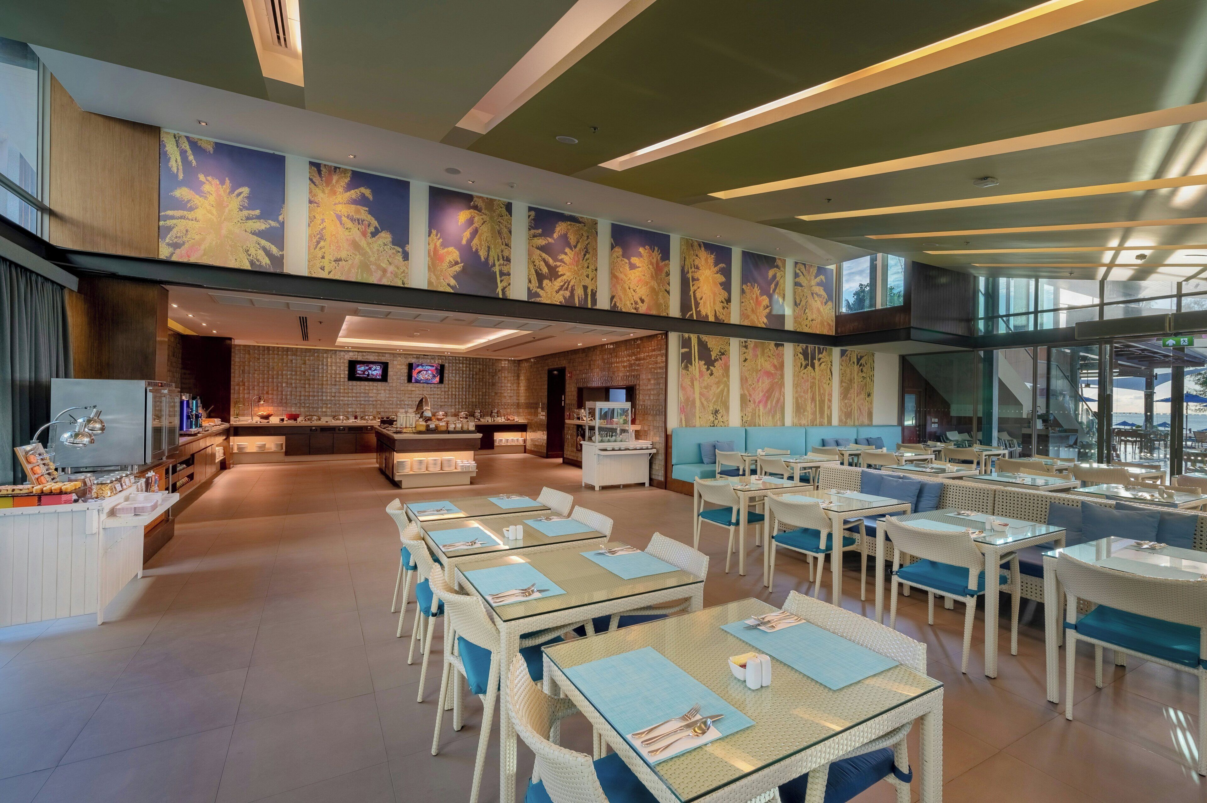 Un amplio vestíbulo de hotel con zona de bar, asientos y un gran mural.