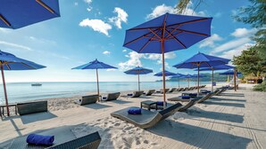 A beach with lounge chairs and blue umbrellas. - OZO Chaweng Samui (Koh Samui)