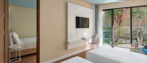 Habitación de hotel con dos camas, un televisor montado en la pared, un escritorio con silla y un ventanal con vistas a zonas verdes.
