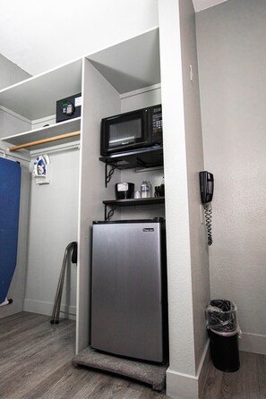 A compact kitchenette with a refrigerator, microwave, and a telephone. - Urban Boutique Hotel (San Diego)