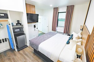 A hotel room with a bed, a television, a coffee machine, and a desk with a computer.