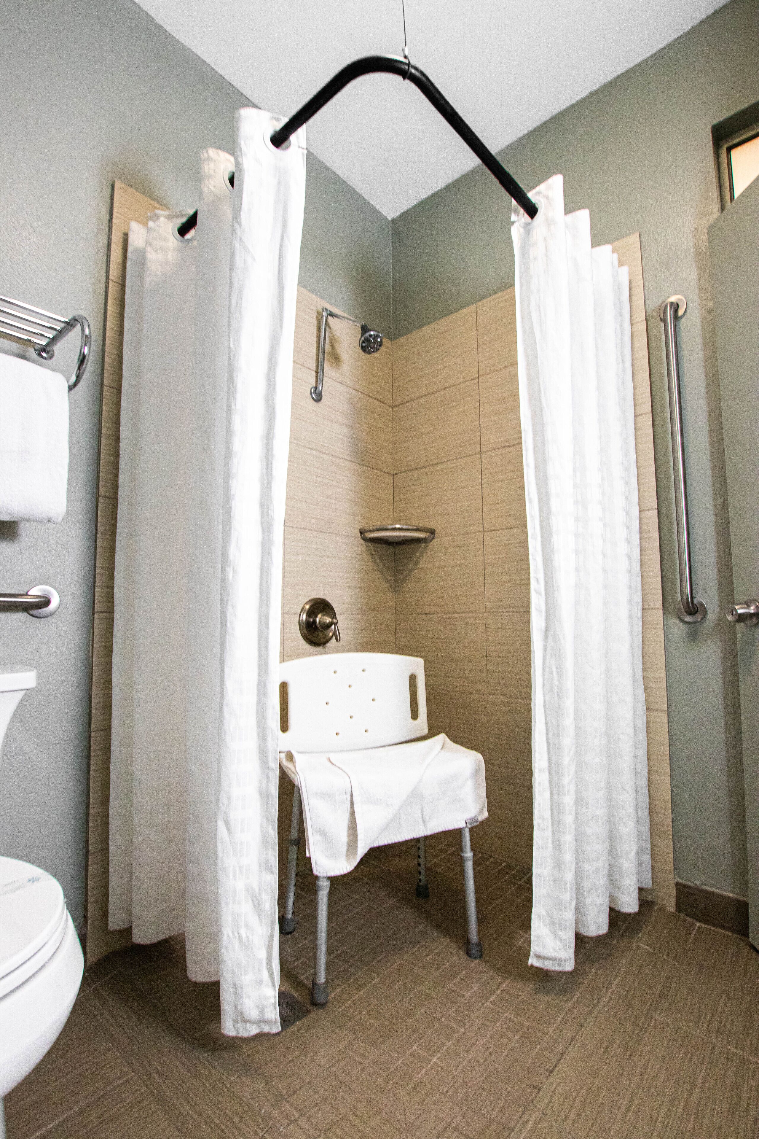 A bathroom with a shower, a toilet, and a grab bar.
