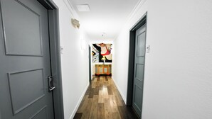 Un pasillo con puertas grises, piso de madera y un mural de pared colorido.