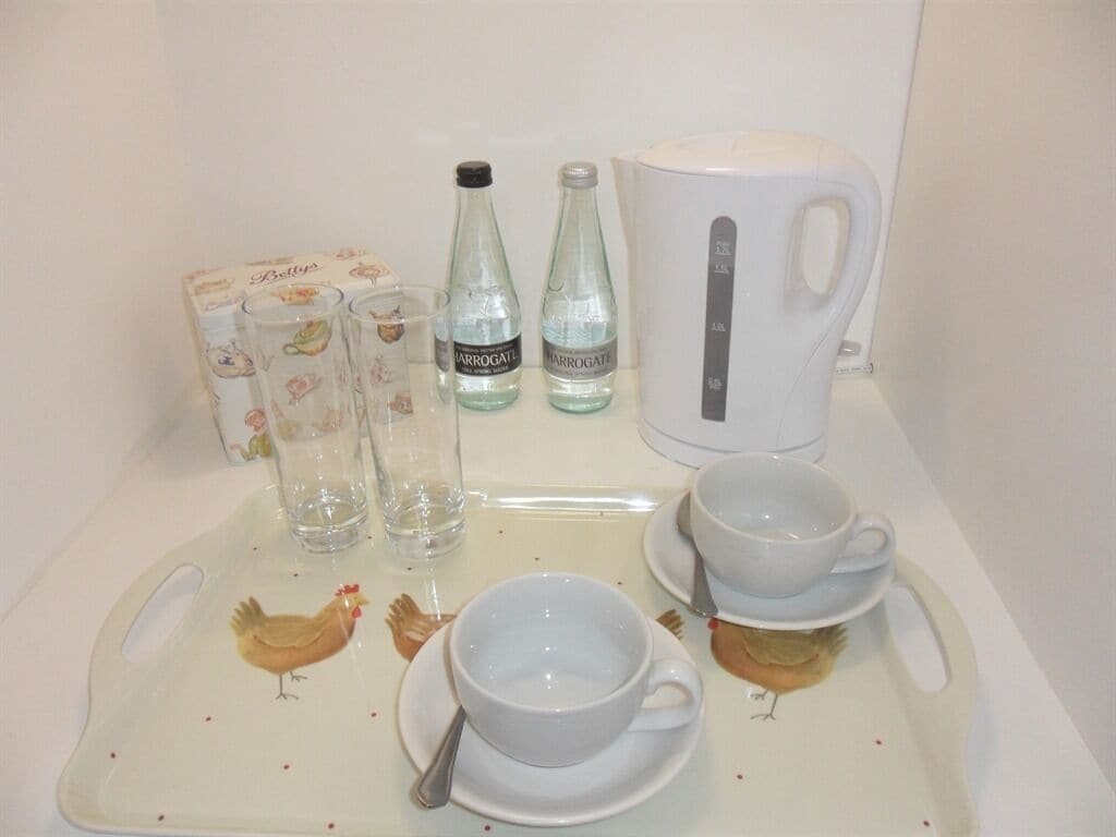 A tray with a white mug, two cups, a box of tissues, and two bottles of water.