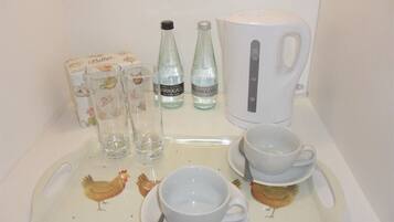 A tray with a white mug, two cups, a box of tissues, and two bottles of water.