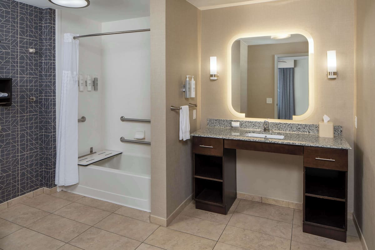 A modern bathroom with a shower, a vanity with a mirror, and a towel rack.