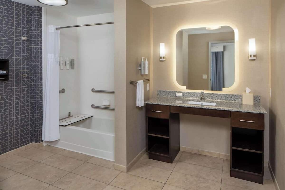 A modern bathroom with a shower, vanity with a mirror, and a towel rack.