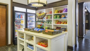 A well-lit snack bar with a variety of snacks and beverages, a hanging chair, and a view of the hallway.