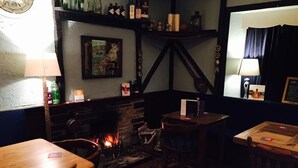 A cozy corner with a fireplace, wooden furniture, and a wall clock. - The Bugle Inn (St Austell)