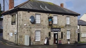 A stone building with a black sign reading "The Riggs". - The Bugle Inn (St Austell)
