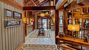 A wooden interior with a central table, framed pictures on the walls, and a view through an open door. - Puyuhuapi Lodge & Spa (Cisnes)