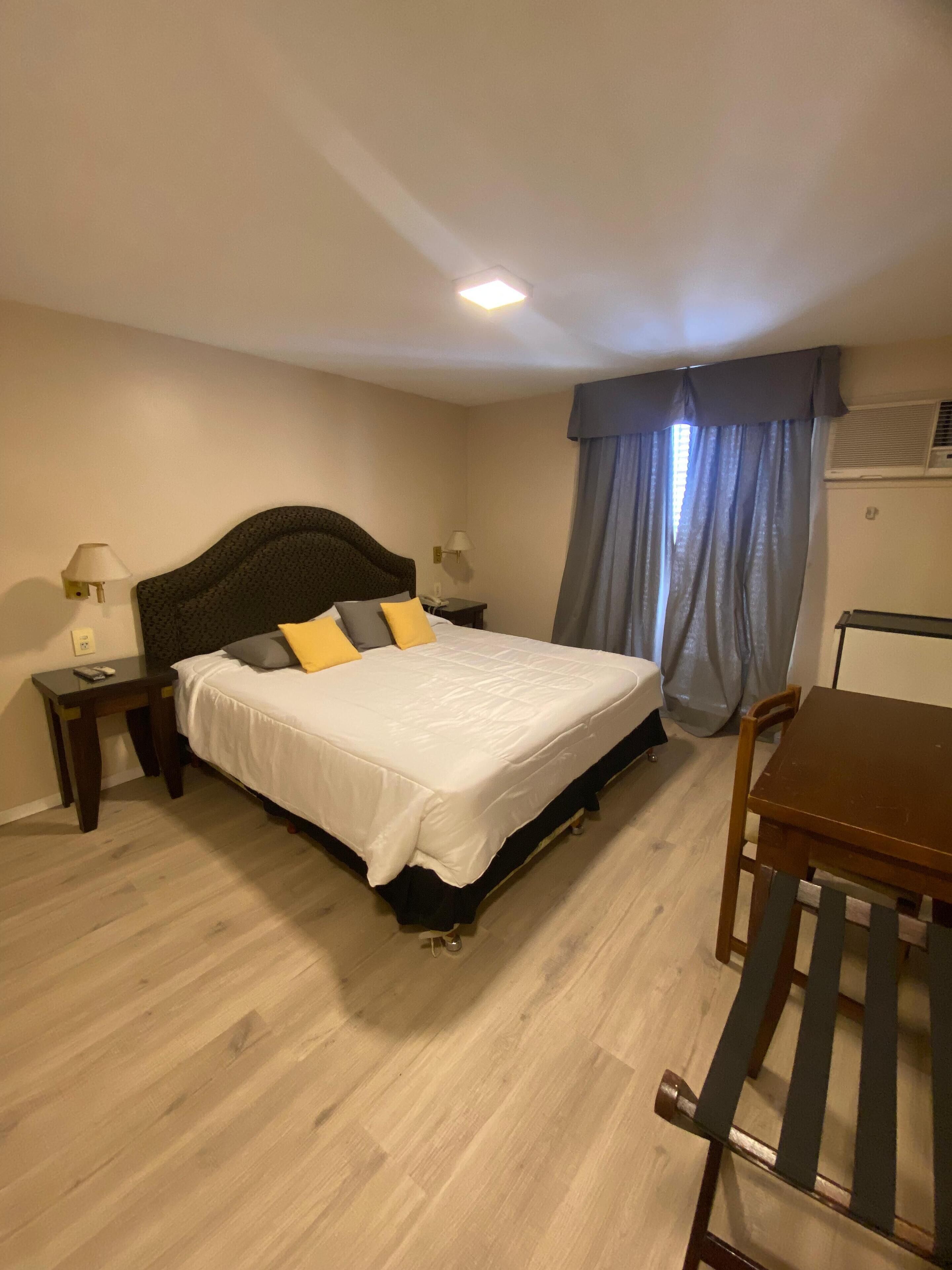 Hotellihuone, jossa on sänky, yöpöydät, työpöytä ja tuoli.