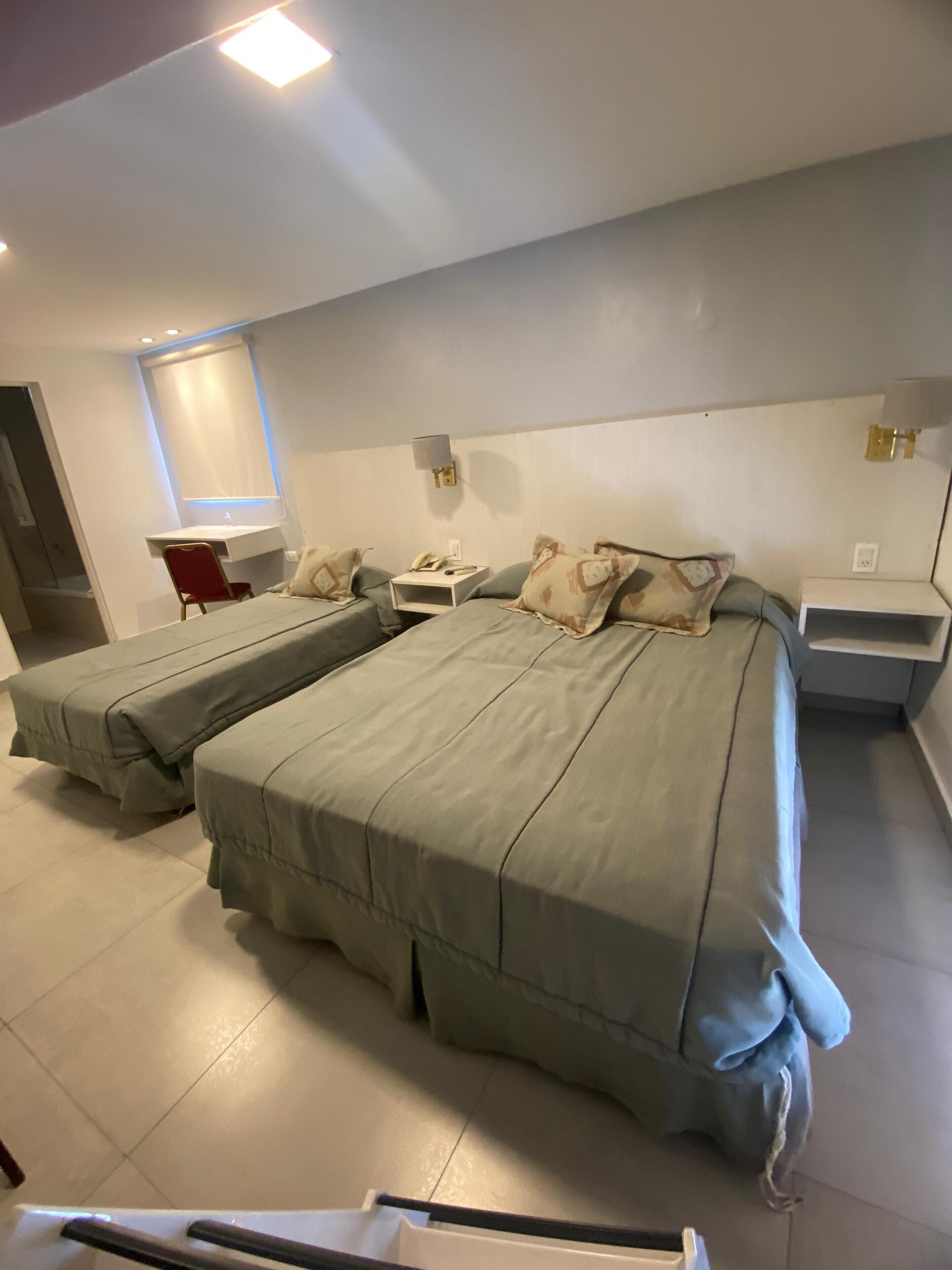 Een moderne slaapkamer met twee bedden, een bureau en een stoel.