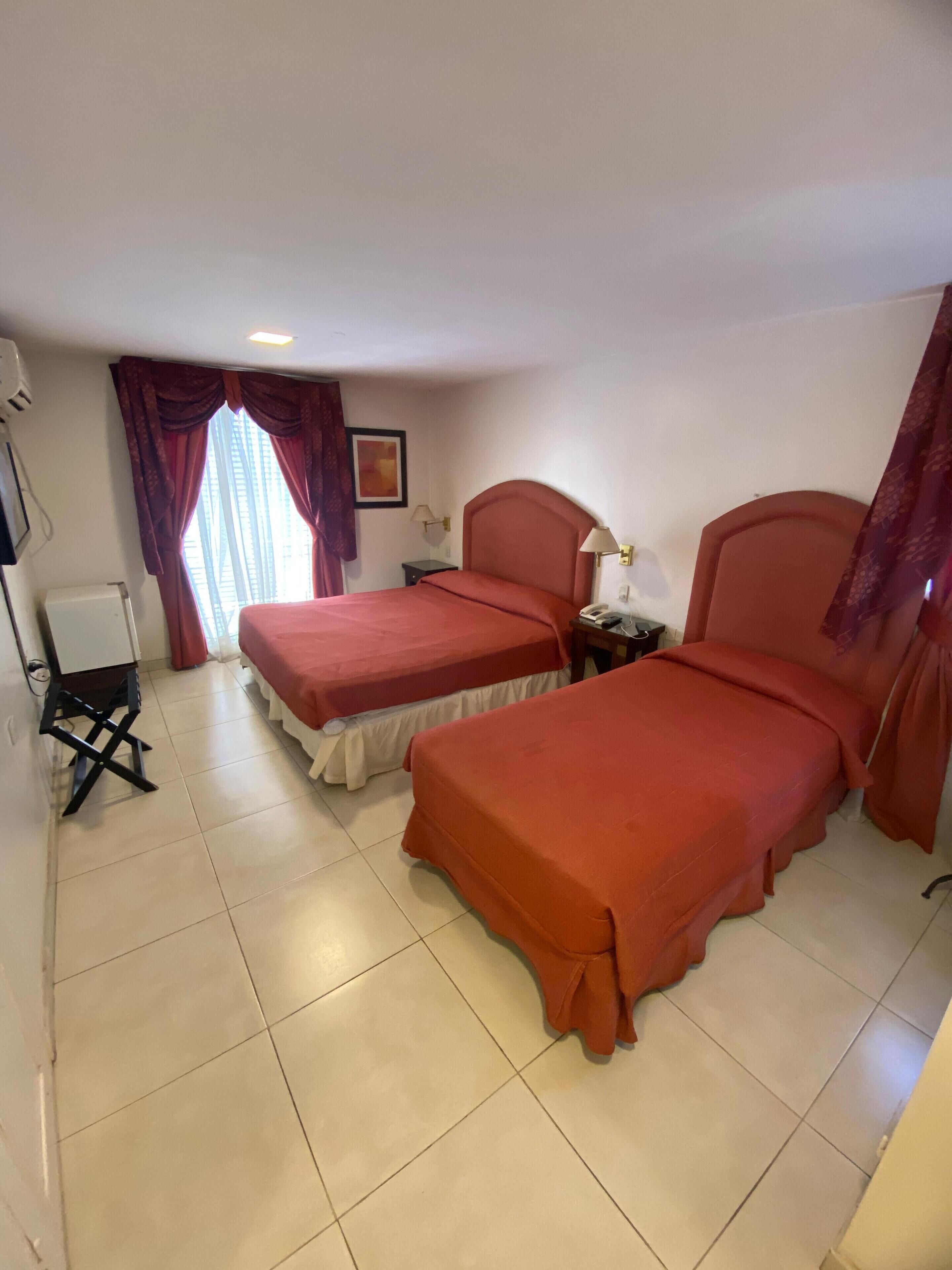 A hotel room with two beds, a desk, and a chair.