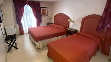 A hotel room with two beds, a desk, and a chair.