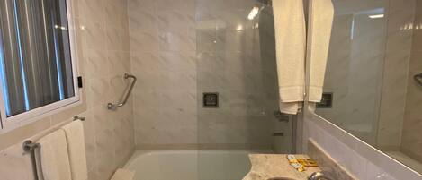 A modern bathroom with a bathtub, a sink with a marble countertop, and a large mirror.