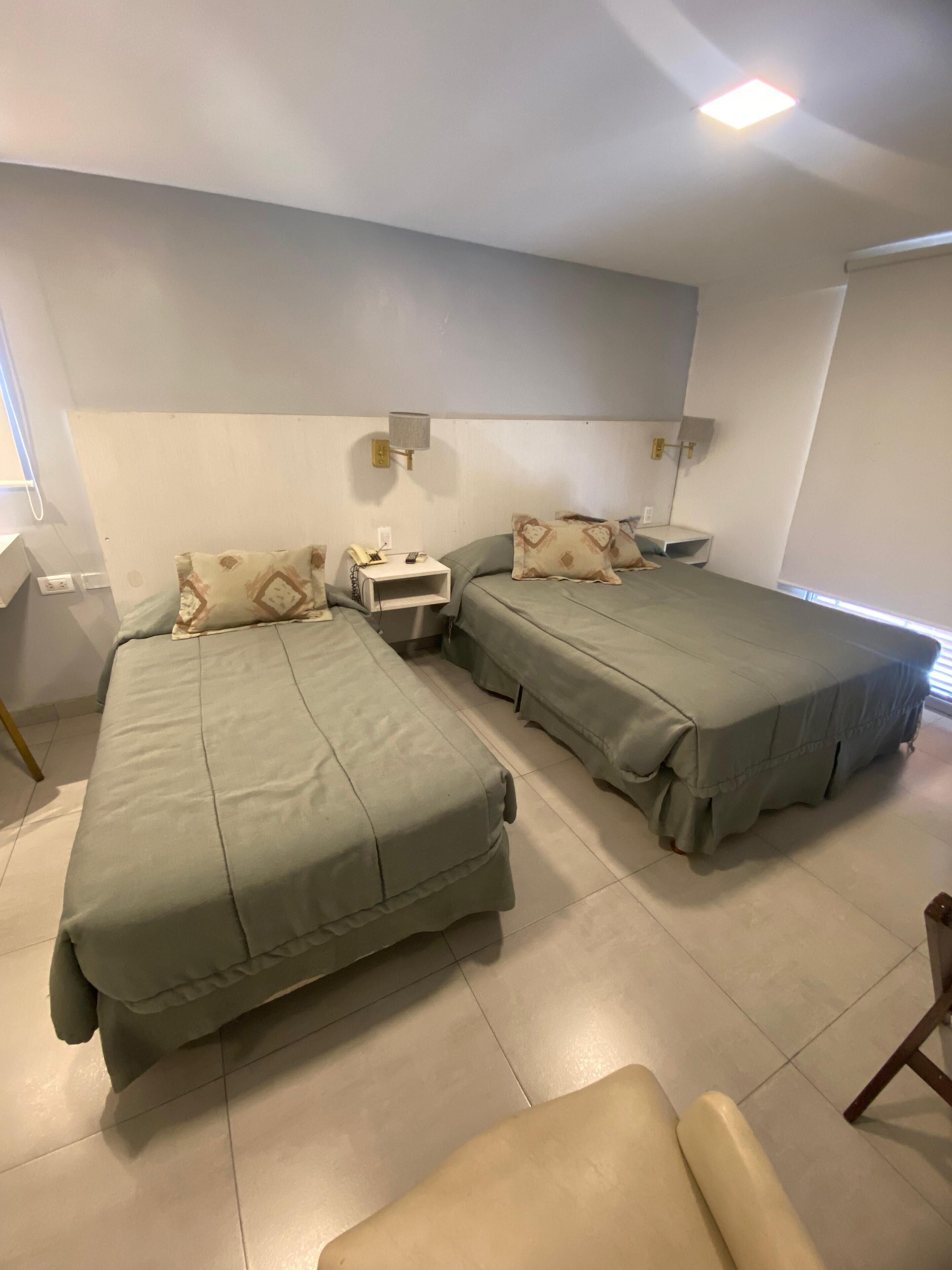 Una habitación con dos camas, una mesita de noche y una silla.