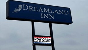 Señal para Dreamland Inn con un aviso de 'ABIERTO BAJO NUEVA GERENCIA'.