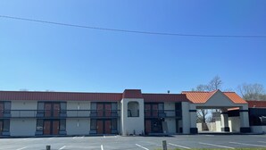 Un edificio de dos pisos con techo rojo y un estacionamiento al frente.