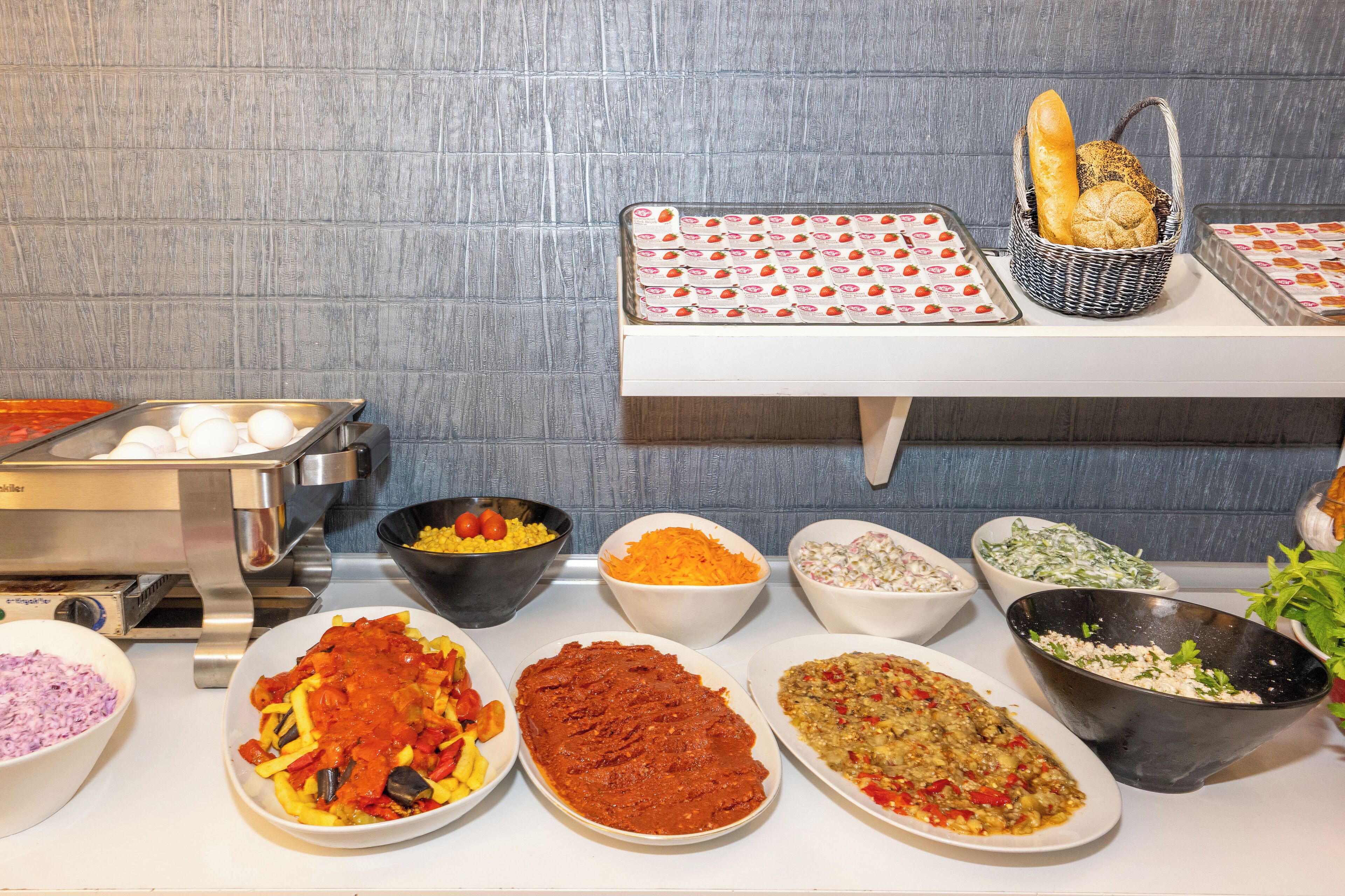 A buffet with various dishes, including salads, pasta, and bread.