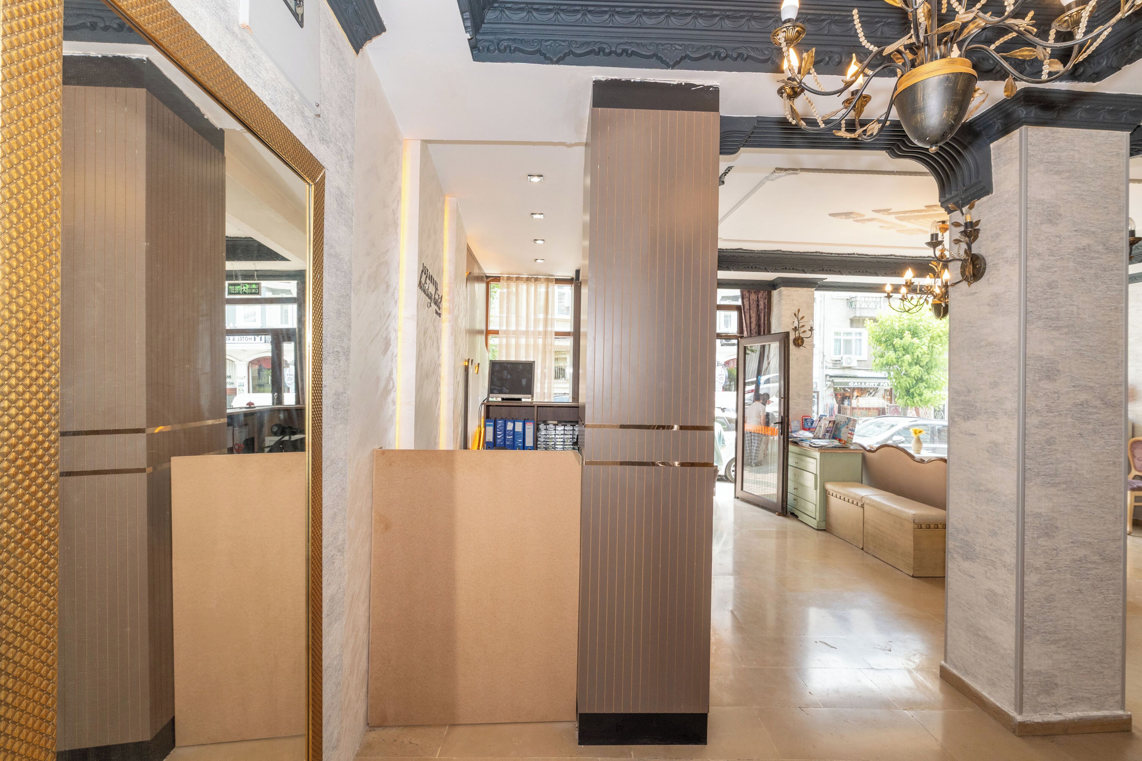A modern hotel lobby with a reception desk, a seating area, and a chandelier.