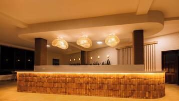 A reception area with a stone-textured counter, three woven pendant lights, and a wooden column.