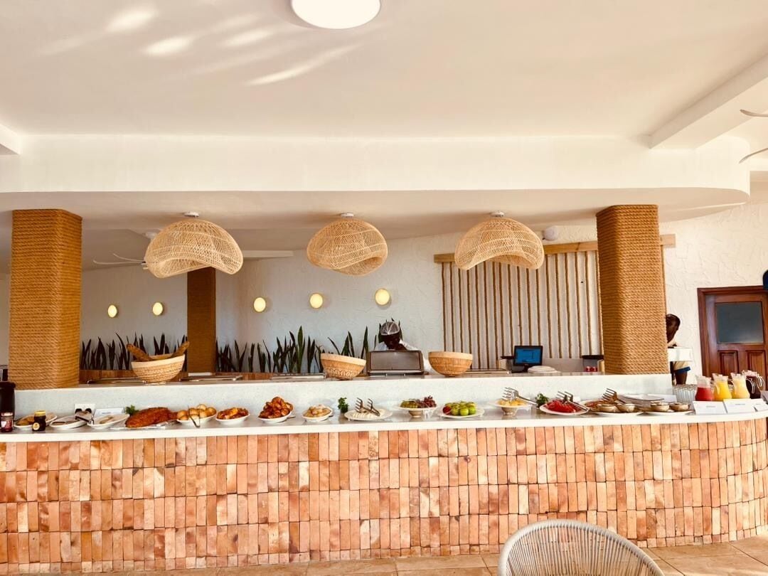 A buffet setup with a brick counter, woven baskets, and a modern ceiling design.