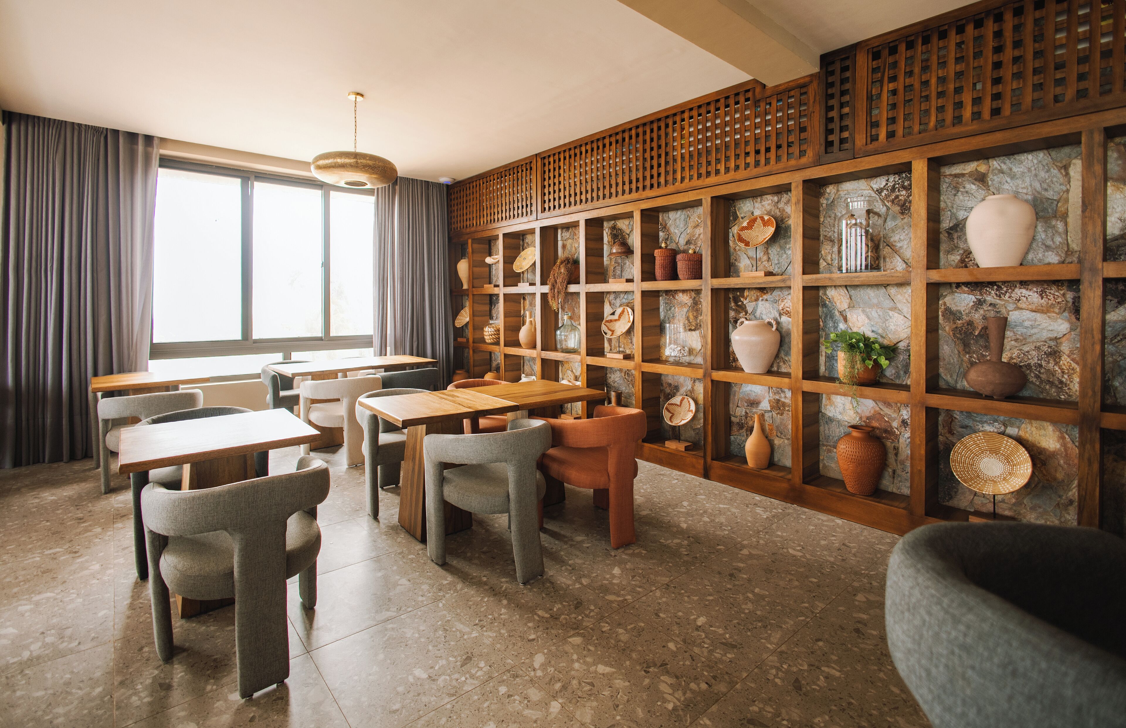 A restaurant with a stone wall display, wooden tables, and chairs.