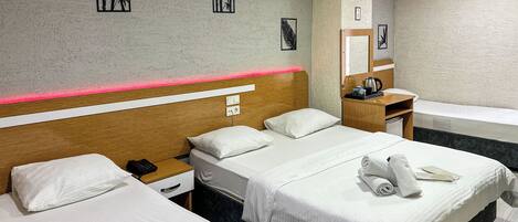 Habitación de hotel con dos camas, un cabecero de madera, una mesita de noche con un teléfono, un escritorio pequeño con un espejo y otra mesita de noche.