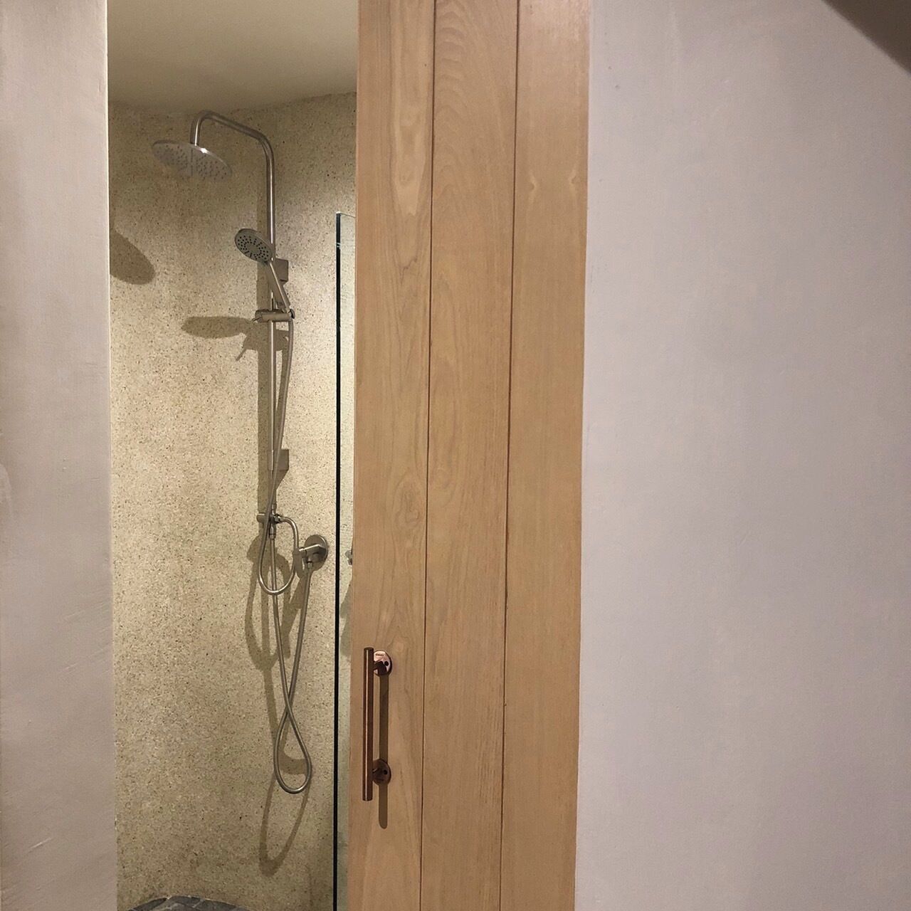 Une douche équipée d’un pommeau de douche à main et d’un robinet fixé au mur.