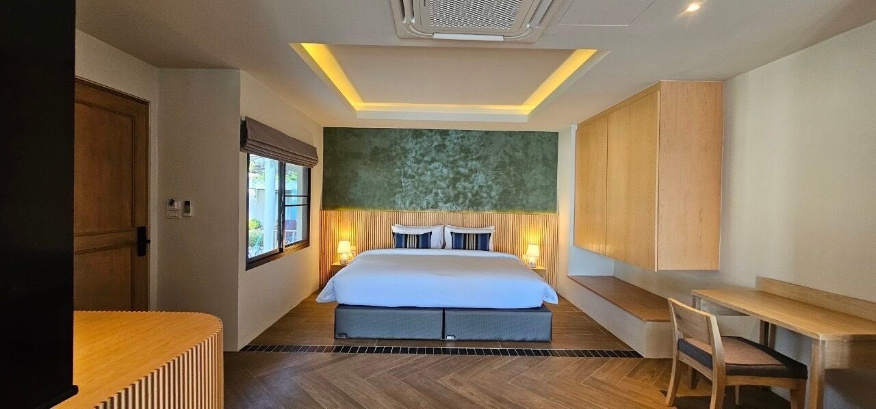 Une chambre d’hôtel moderne avec un grand lit, des tables de chevet, un bureau et une fenêtre.