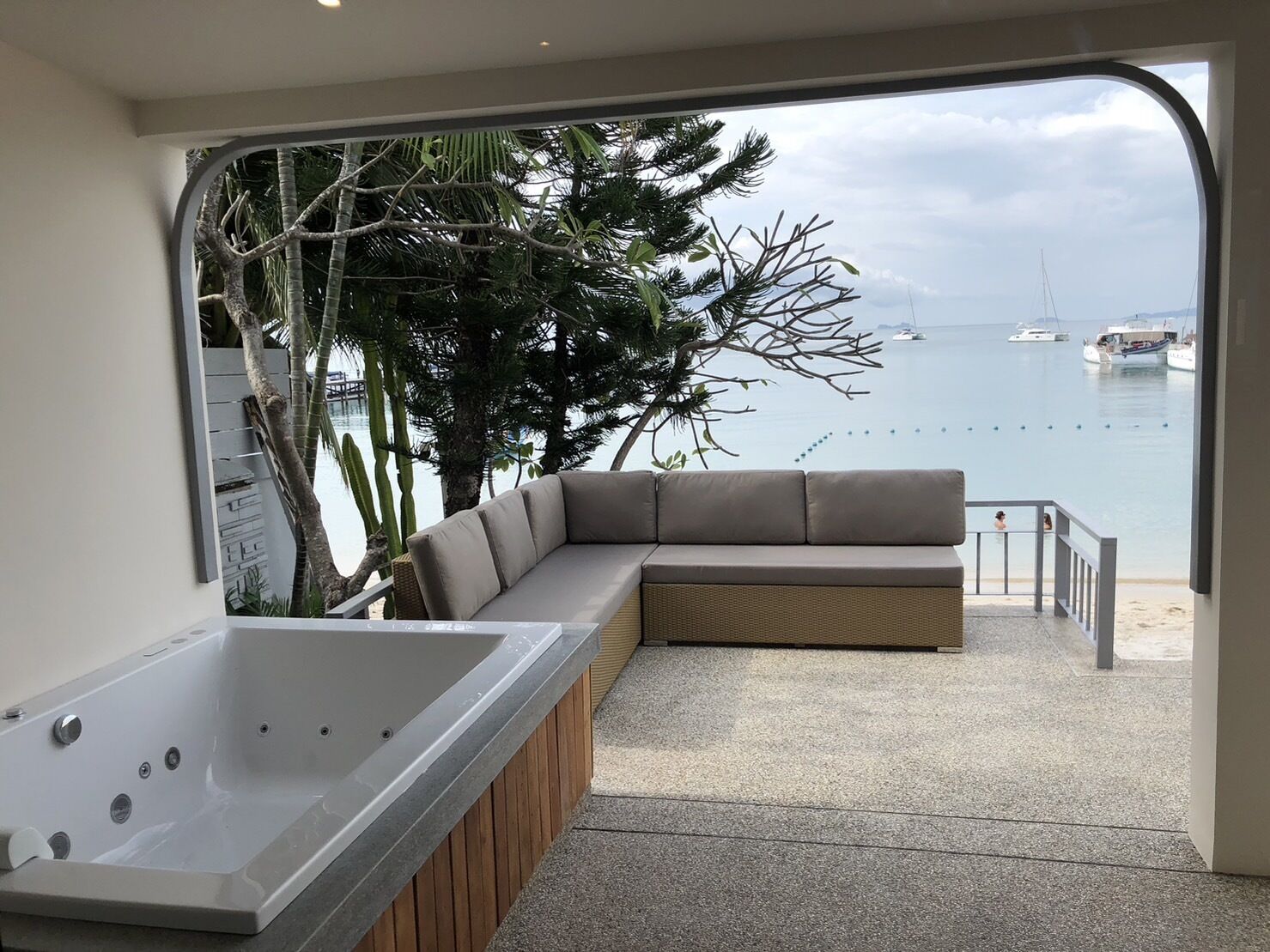 A modern outdoor seating area with a built-in hot tub, overlooking a marina with boats.