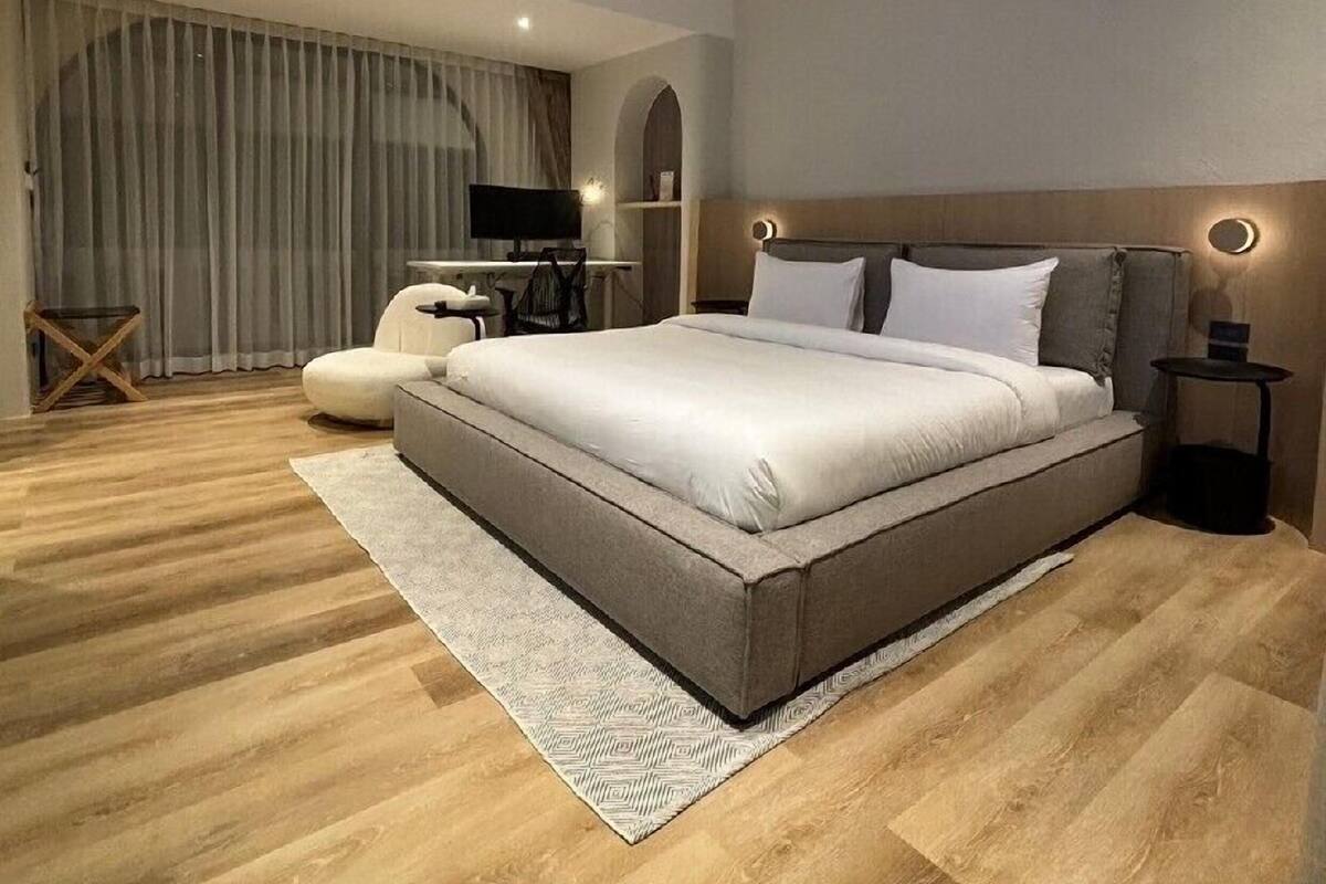 A modern bedroom with a large bed, a desk, and a television.
