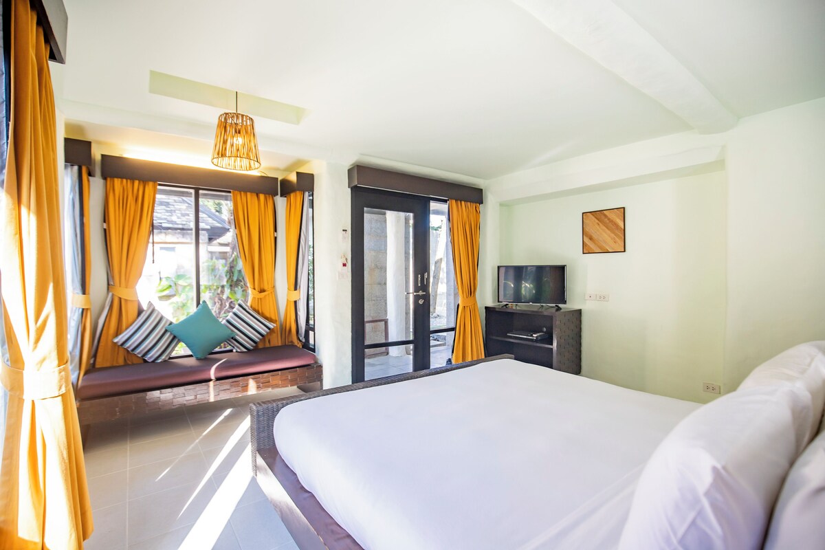 Una habitación de hotel con una cama grande, televisión y ventana con cortinas.