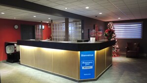 A reception desk with a 'Bienvenue' sign, a clock, and a Christmas tree. - Rodeway Inn (Gaspé)