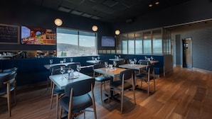 A restaurant with tables and chairs, a bar area, and large windows offering a view. - Rodeway Inn (Gaspé)