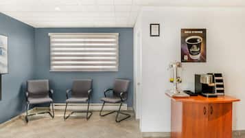 A reception area with three chairs, a coffee machine, and a framed poster on the wall.