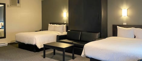 Une chambre d’hôtel avec deux lits, un canapé, une petite table et deux lampes fixées au mur.