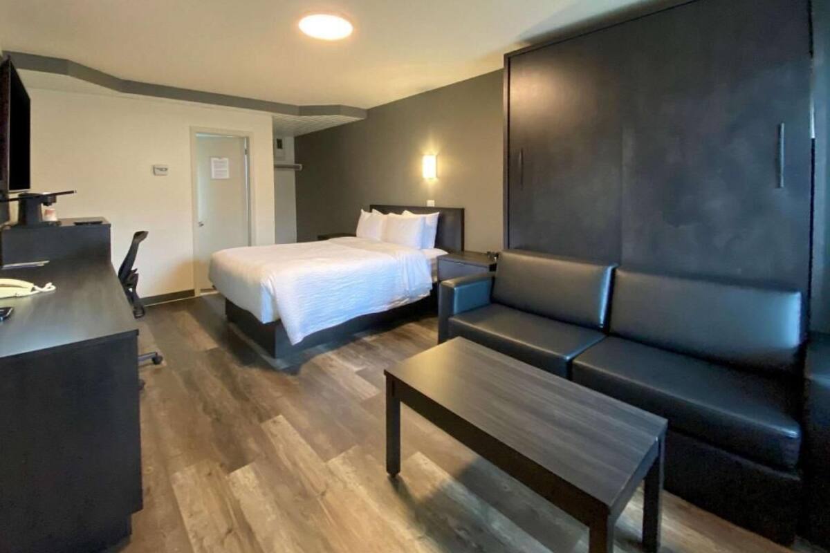 A hotel room with a bed, a sofa, a desk, and a wardrobe.