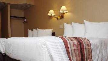 A hotel room with a double bed, two wall-mounted lamps, a headboard, and a bedside table.