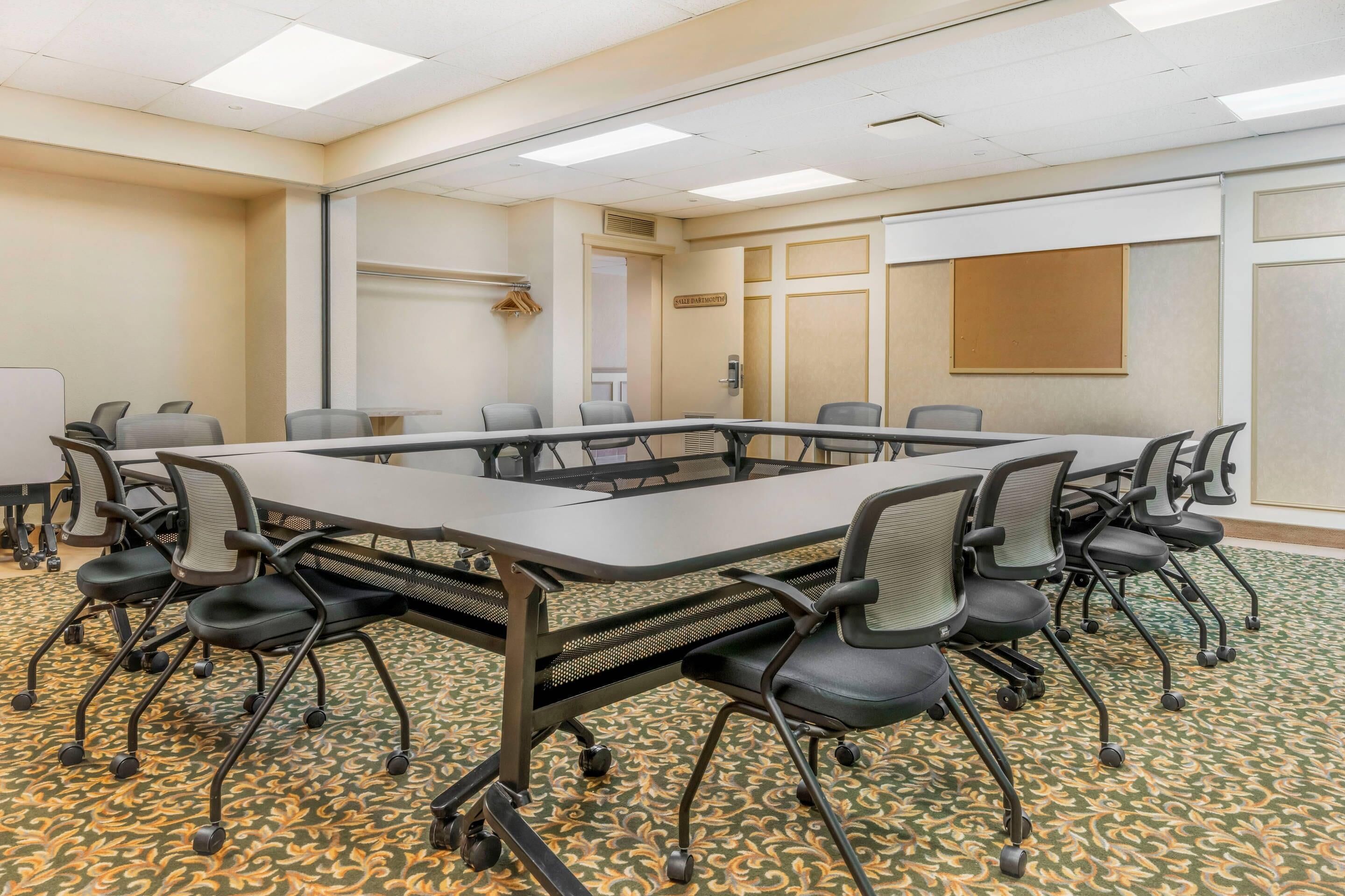 Une salle de conférence avec une longue table, de nombreuses chaises et un sol recouvert de moquette.