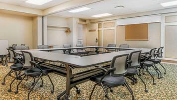 Une salle de conférence avec une longue table, de nombreuses chaises et un sol recouvert de moquette.