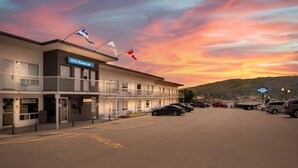A motel with multiple rooms, a parking lot, and a scenic sunset view. - Rodeway Inn (Gaspé)