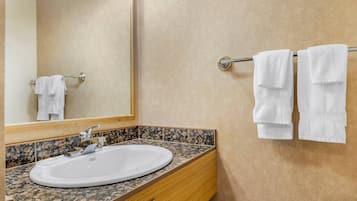 Un baño con lavamanos, espejo y toallero.