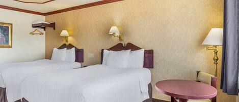 A hotel room with two beds, a round table, and a chair.