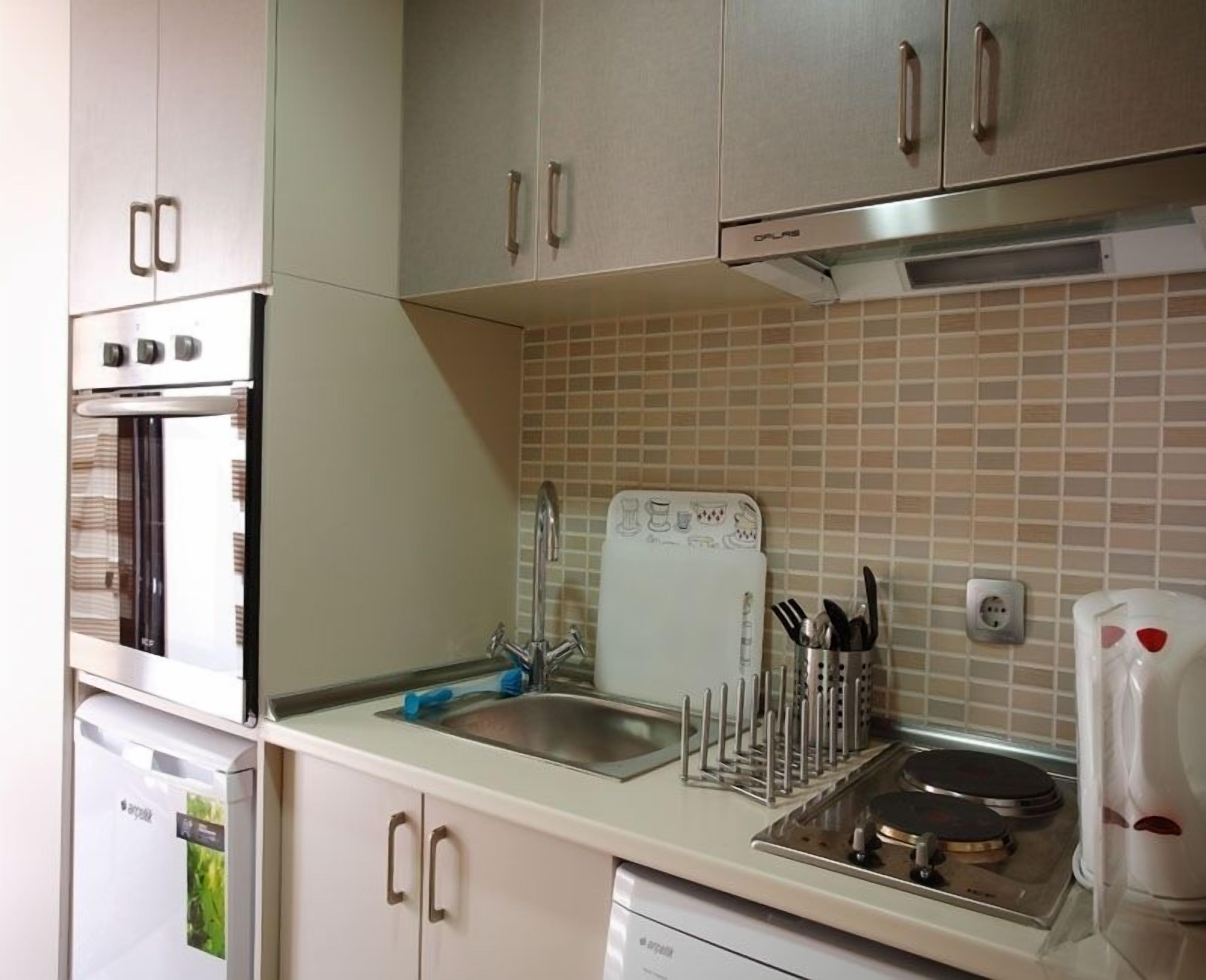 Een keuken met roestvrijstalen apparatuur, een betegelde spatwand en een afwasschaal.