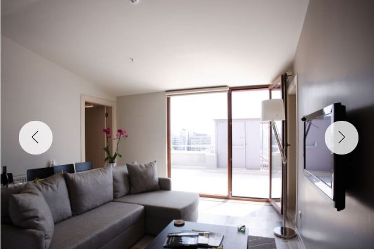A modern living room with a sofa, coffee table, and a TV mounted on the wall.
